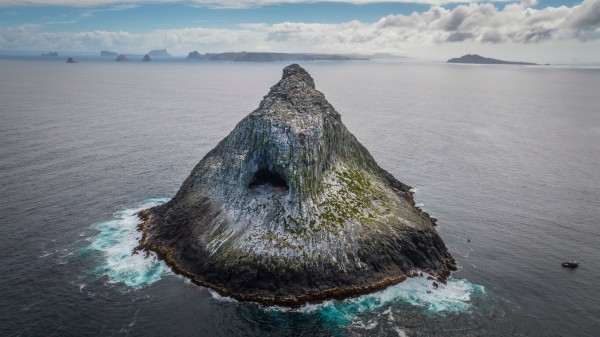 High angle shot of large rocky islet the shape of a pyramid.